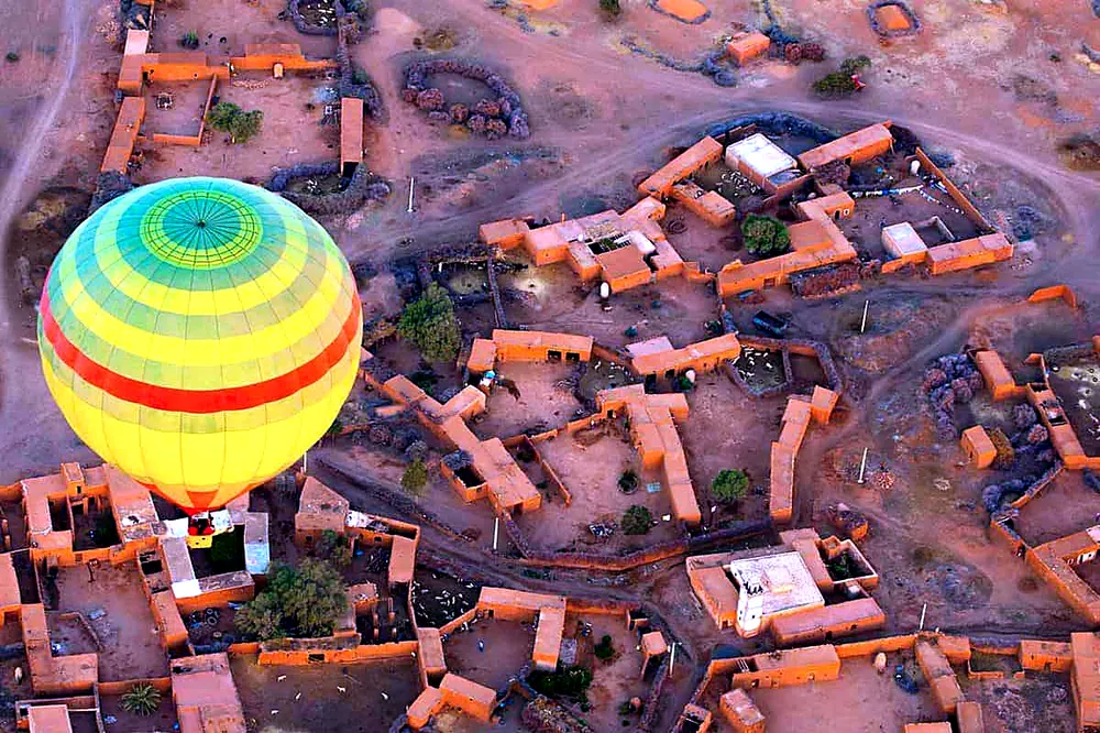 Balloon basket drifting over Marrakech palm groves at sunrise